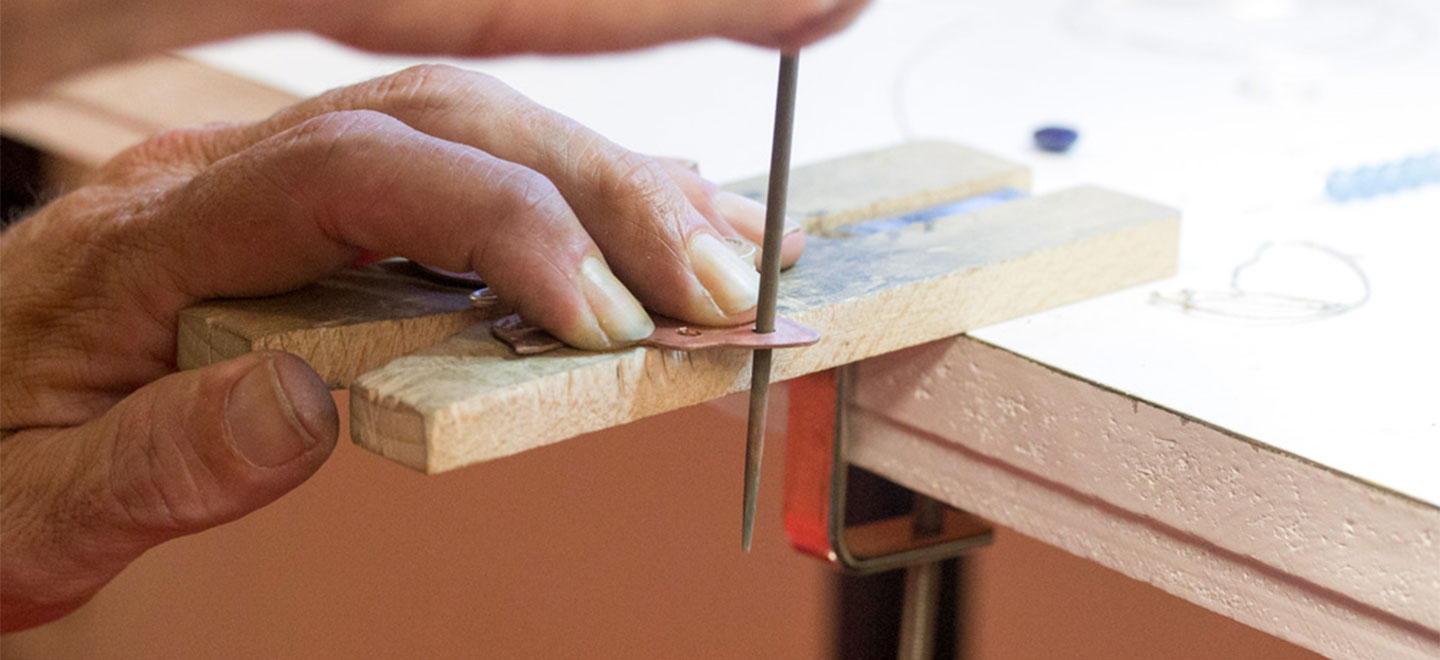 Jeweler using a round filer to smooth the inside of a jewelry piece