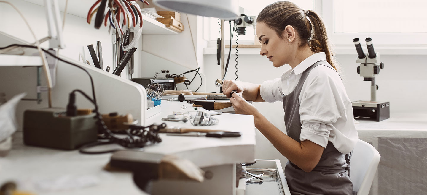 Women jeweler sitting at jewelry bench setting a stone