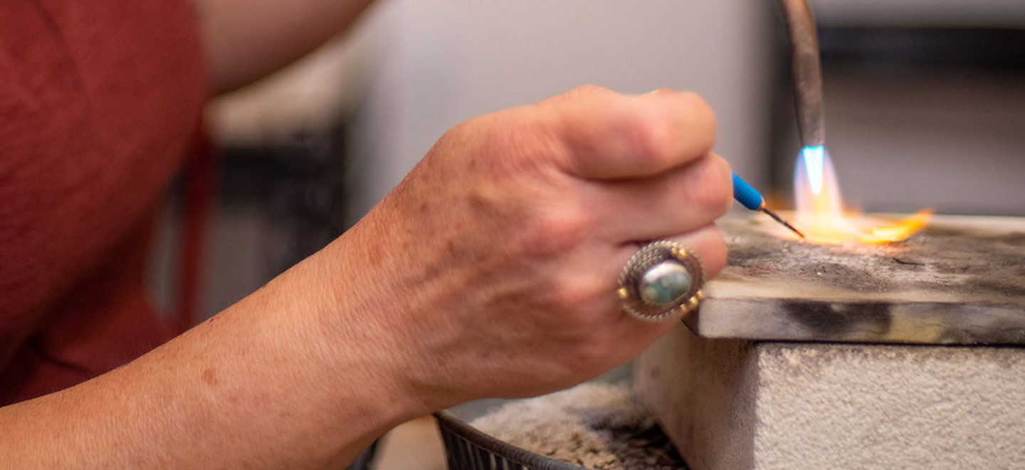 Hands of a jeweler soldering a piece of jewelry